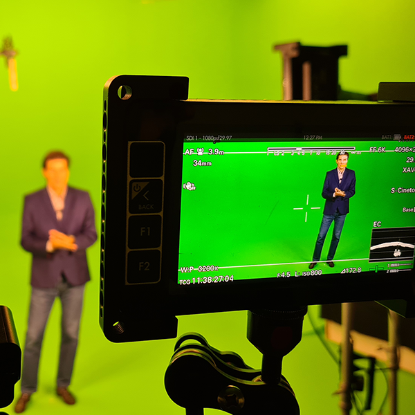A man in a suit is standing in front of a green screen