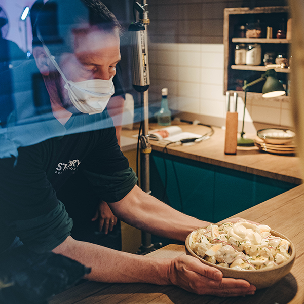Story Production crew on location at a coffee farm A man wearing a mask is holding a bowl of food