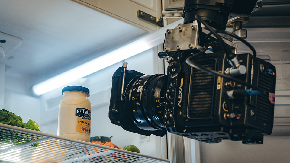 A camera is taking a picture of a bottle of mayonnaise in a refrigerator.