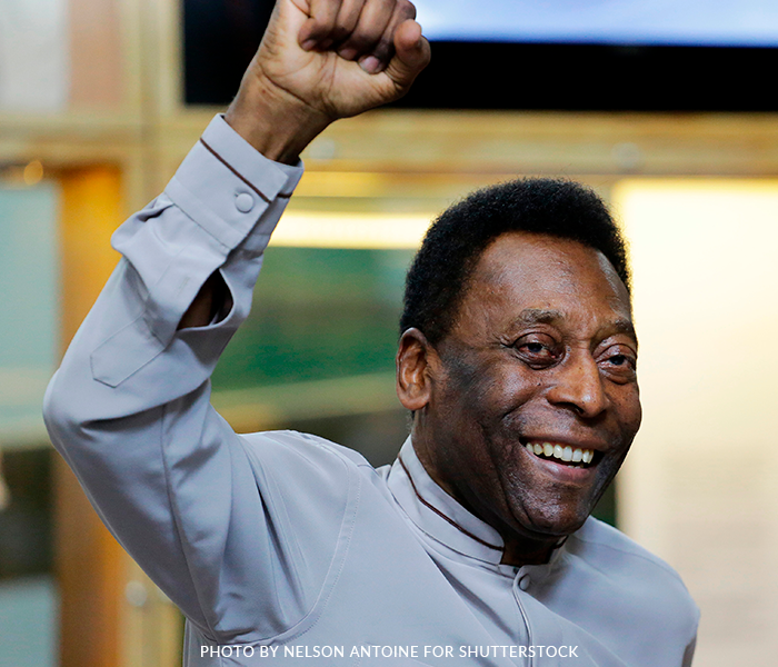 A man with his fist in the air is smiling and wearing a grey shirt