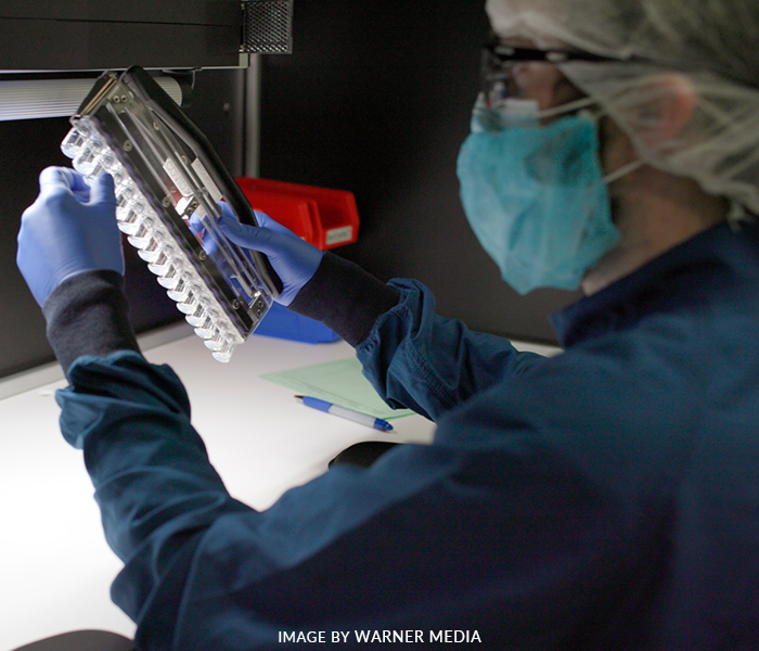 A man wearing a mask and gloves is holding a piece of paper
