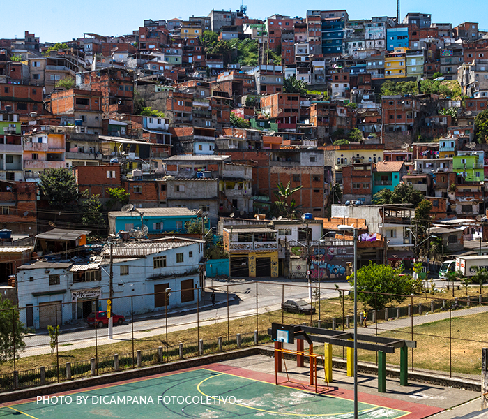 An aerial view of a slum area with a basketball court in the foreground