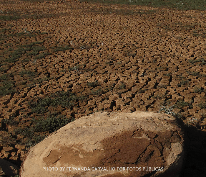 A large rock sits in the middle of a dry desert