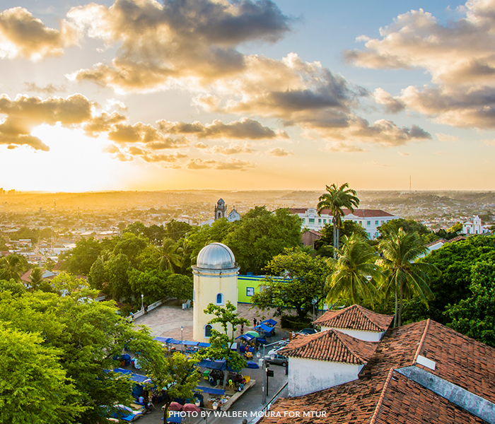 An aerial view of a city at sunset with a observatory in the foreground.