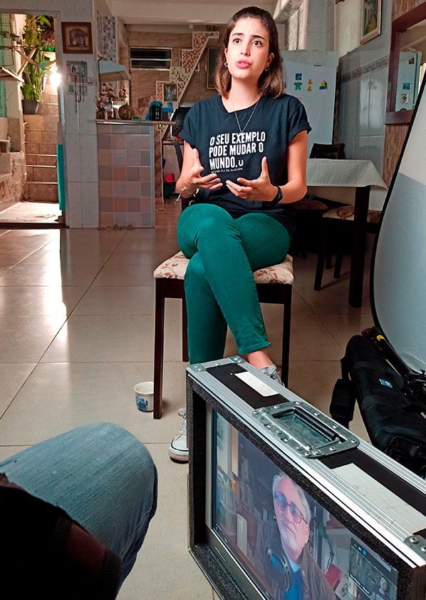 A woman is sitting on a chair in front of a television.