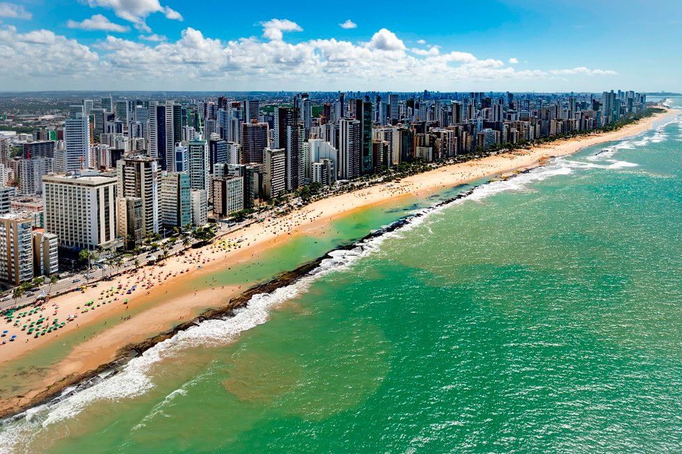 An aerial view of a beach with a city in the background.