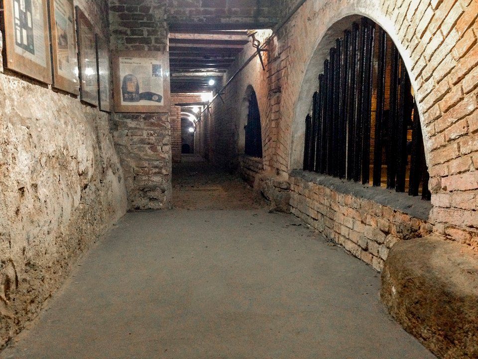 A long hallway with brick walls and arches in a building.