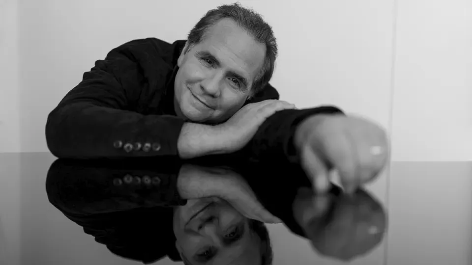 A black and white photo of a man leaning on a table.