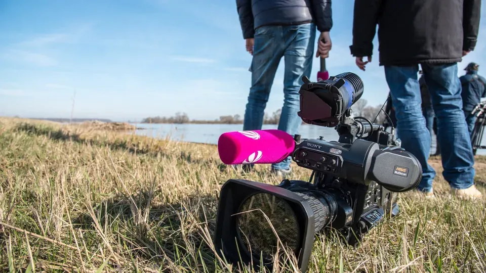 A man is standing next to a camera in a field.