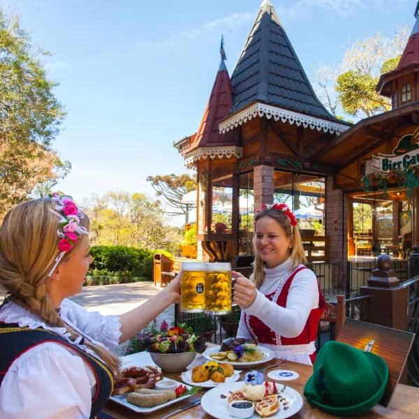 Two women are sitting at a table toasting with beer