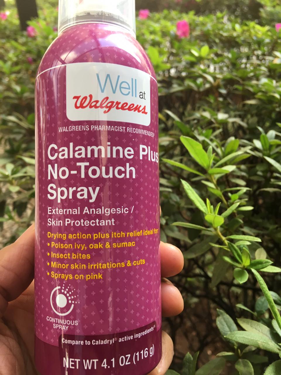 A person is holding a bottle of calamine plus no touch spray