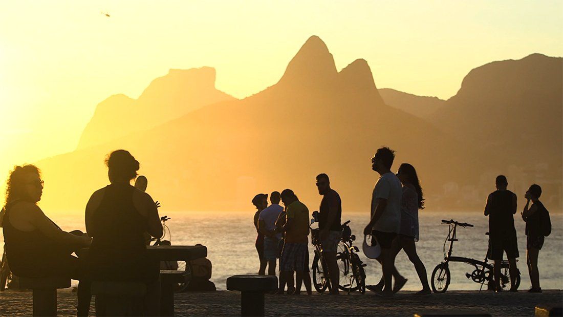 A group of people are standing on a beach at sunset.