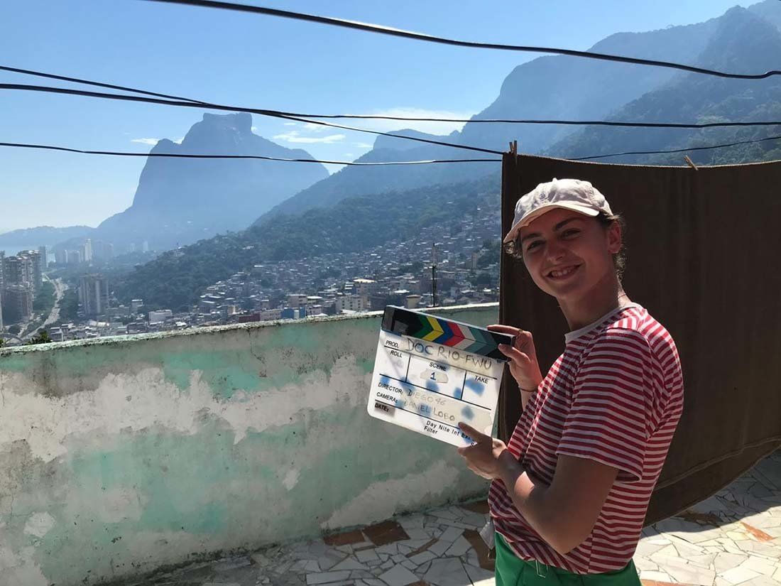 A man is holding a clapper board in front of a mountain range.
