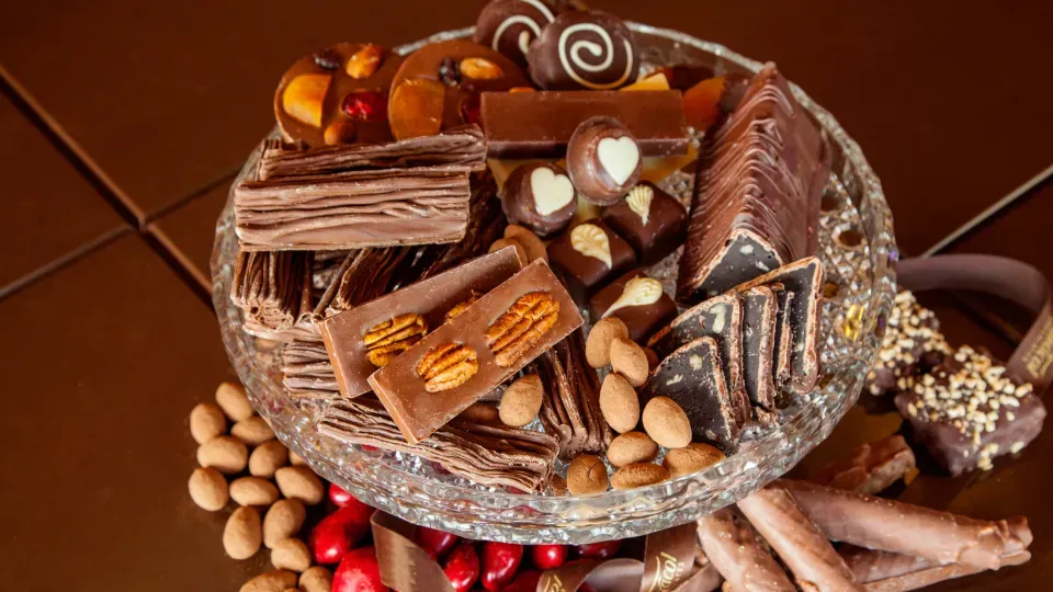 A glass plate filled with chocolates and nuts on a table.