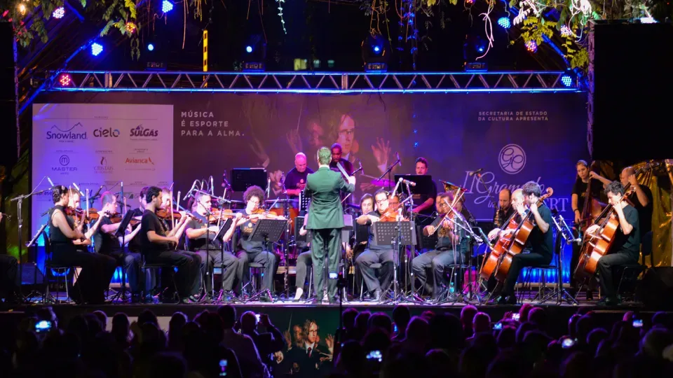 A large orchestra is playing on a stage in front of a crowd.