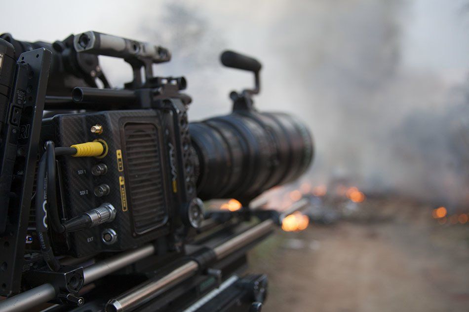 A camera is sitting on a tripod in front of a fire.