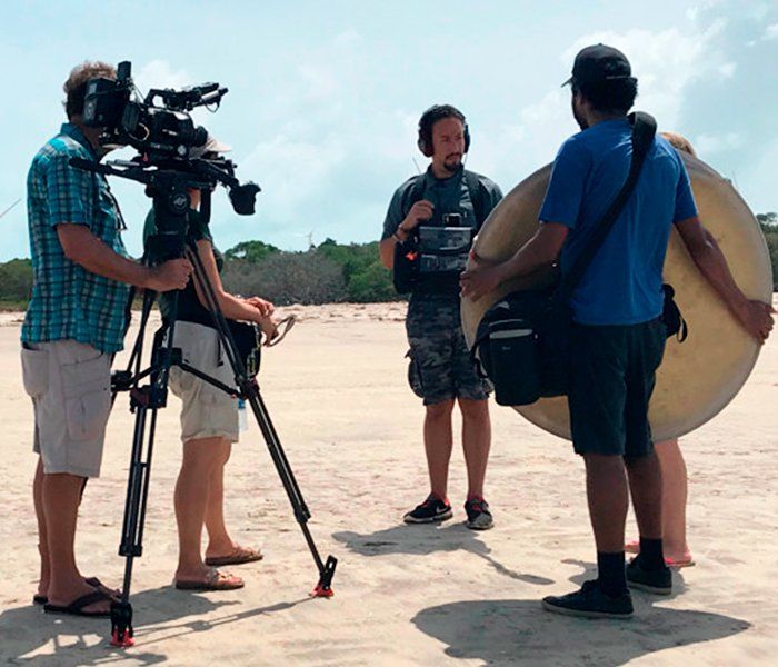 A group of people are standing on a beach talking to each other