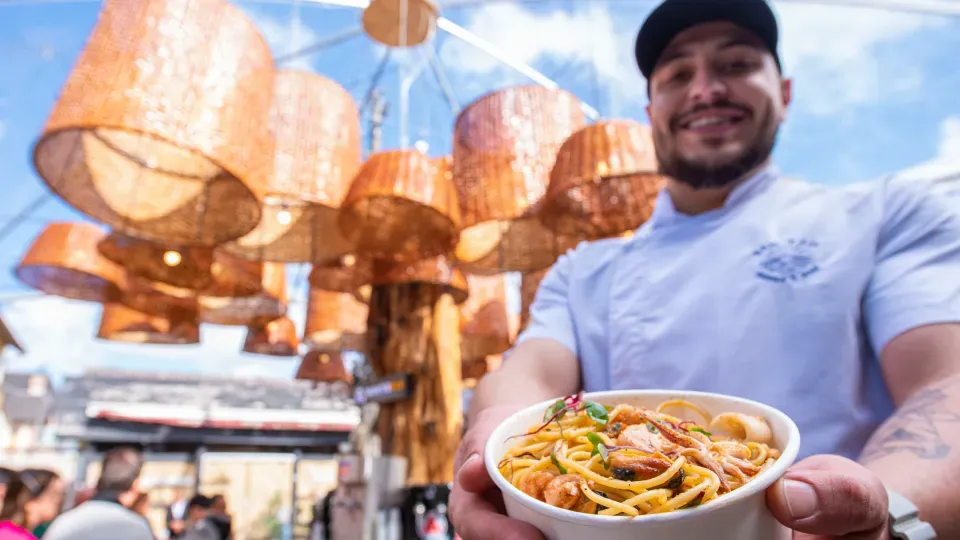 A man is holding a bowl of noodles and shrimp.
