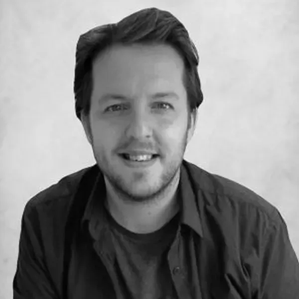A man with a beard is smiling in a black and white photo.