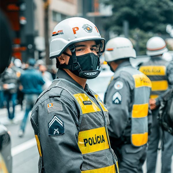 A police officer wearing a helmet and a mask is standing on a street.