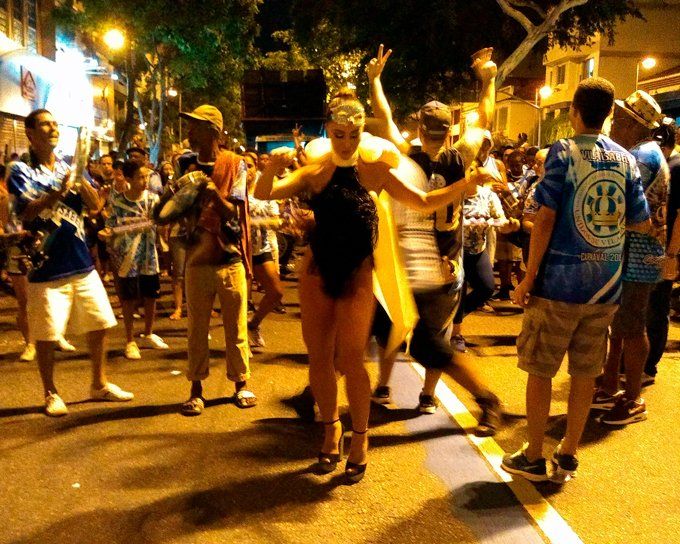 A group of people are dancing on a street and one of them is wearing a shirt that says cb