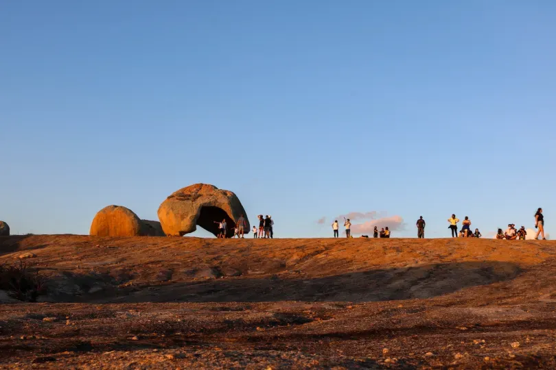 A group of people are standing on top of a rocky hill.