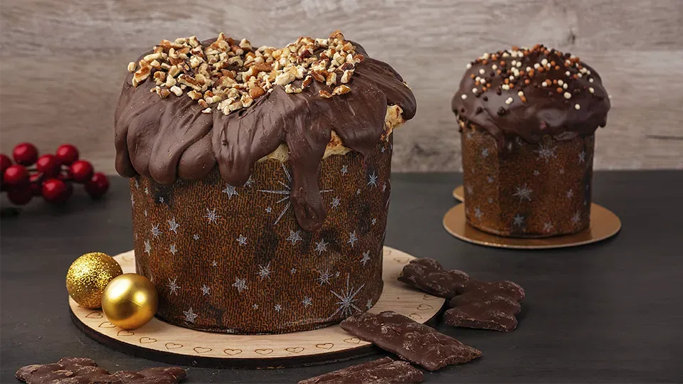 Two chocolate covered cakes are sitting on a wooden table.