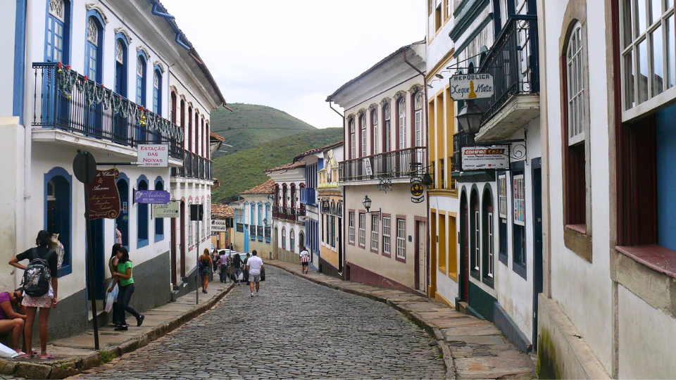 A group of people are walking down a cobblestone street between two buildings.