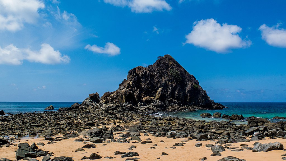 A rocky beach with a large rock in the middle of it