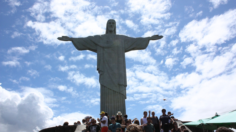 A group of people are standing in front of a large statue of jesus.