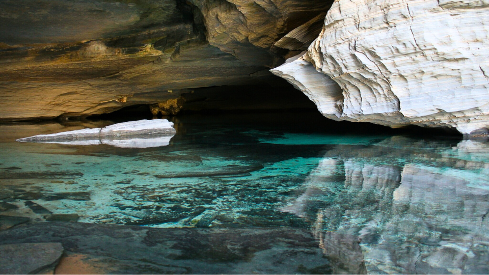 A cave filled with turquoise water and rocks