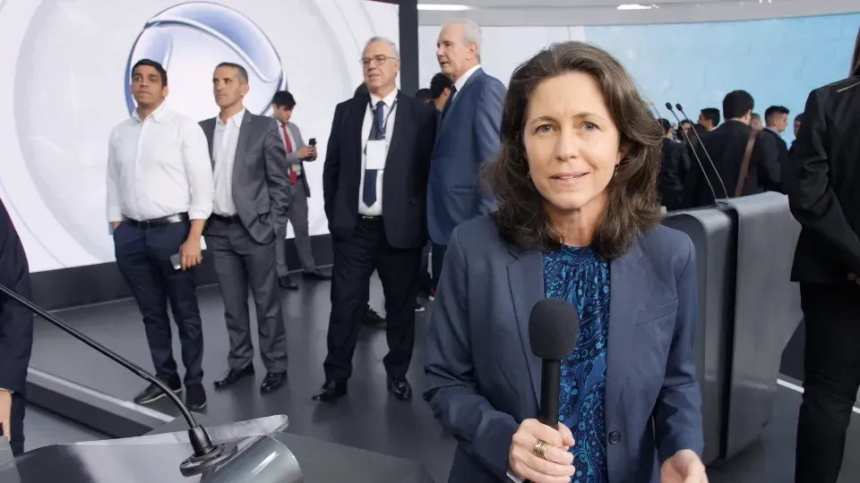 A woman is holding a microphone in front of a group of people.