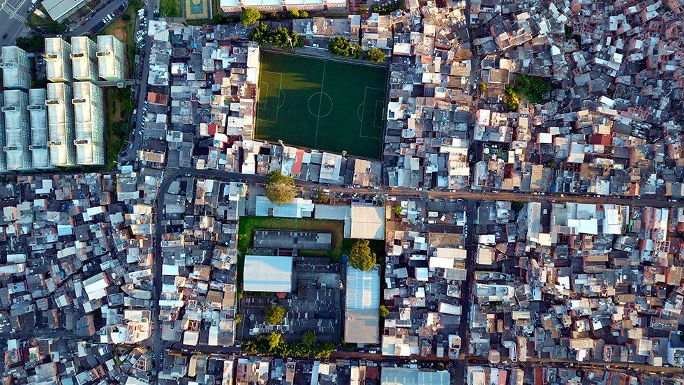 An aerial view of a slum area with a soccer field in the middle.