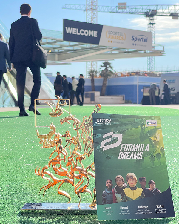 A man in a suit is standing next to a trophy and a book titled formula dreams.
