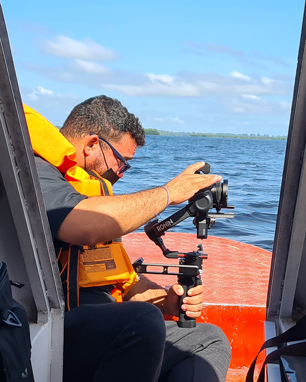 A man in a life jacket is sitting on a boat holding a camera.