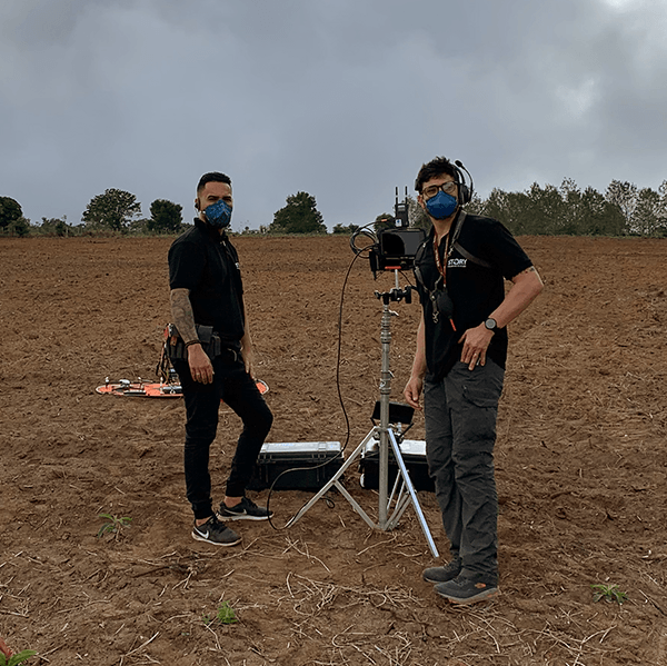 Two men wearing masks are standing in a field.
