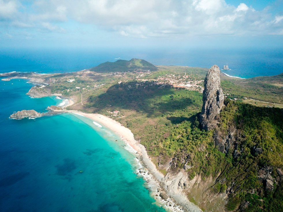 An aerial view of a beach and a mountain in the middle of the ocean.