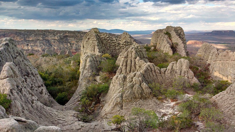 A large rock formation in the middle of a desert with a cloudy sky in the background.