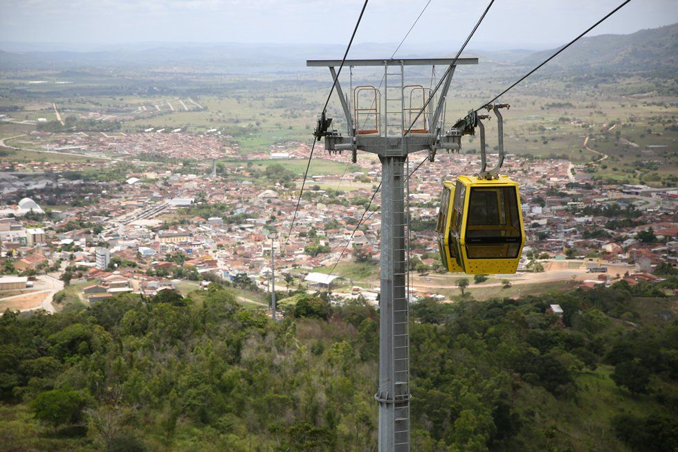 A yellow cable car is going up a hill overlooking a city.