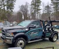 A black tow truck is parked in a parking lot.