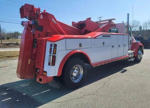 A red and white tow truck is parked on the side of the road.