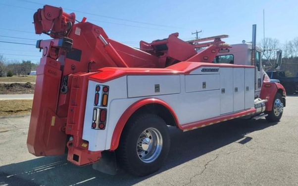 A red and white tow truck is parked on the side of the road