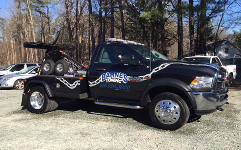 A black tow truck is parked in a parking lot.