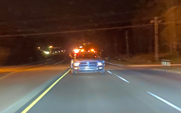 A blue truck is driving down a highway at night.