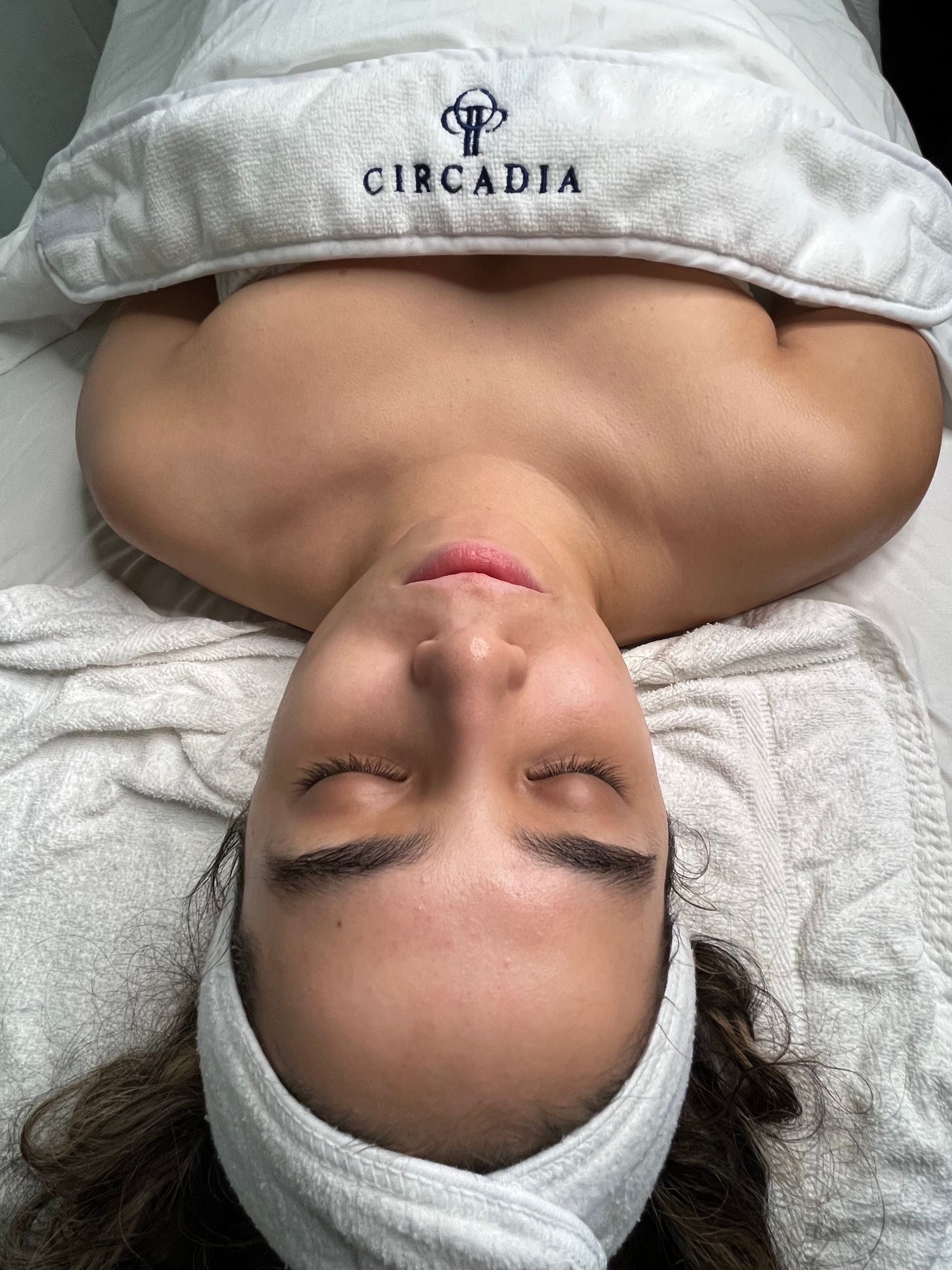 A woman is laying on a massage table with her eyes closed.