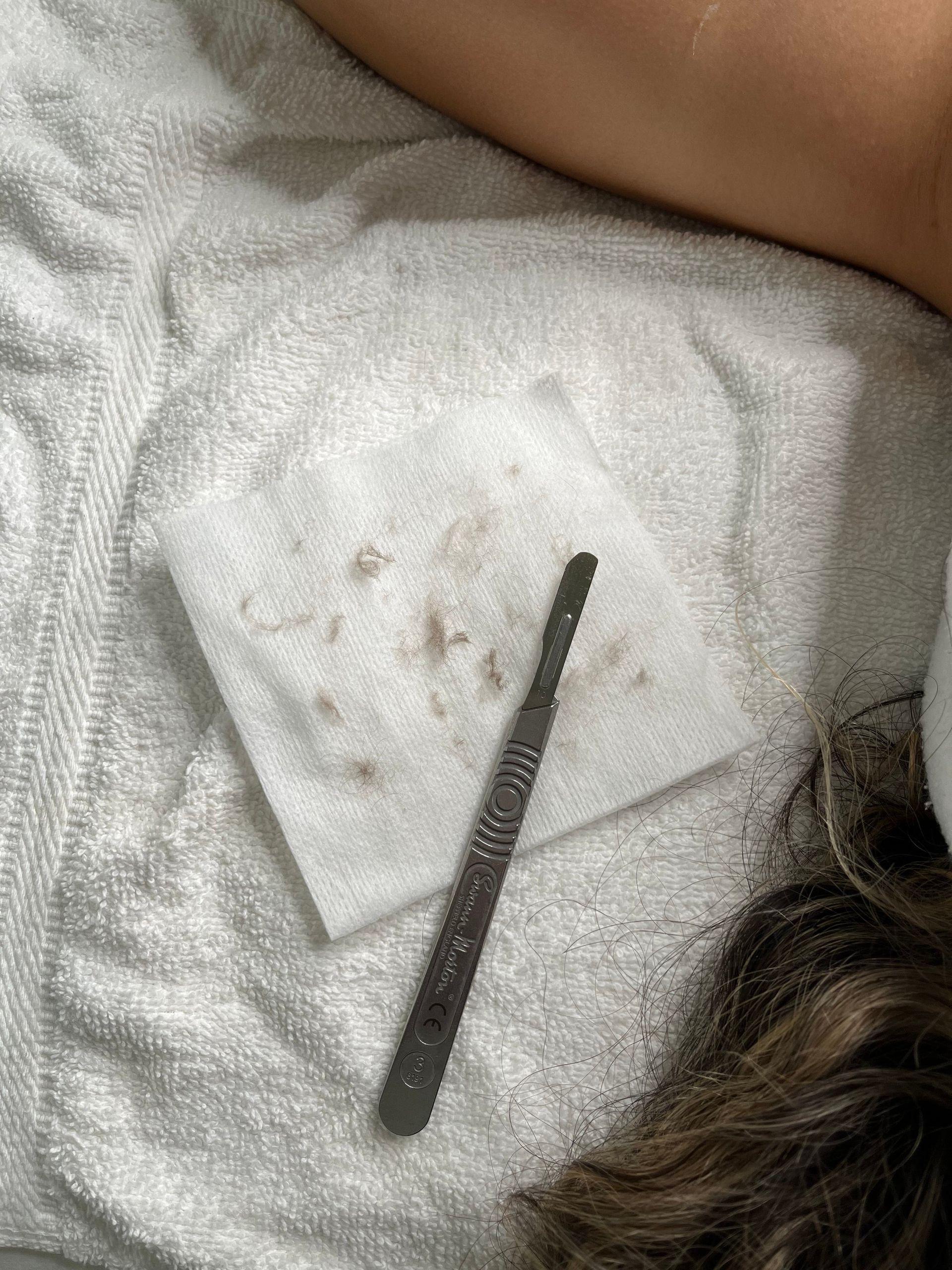 A person is laying on a bed with a towel and a nail file.