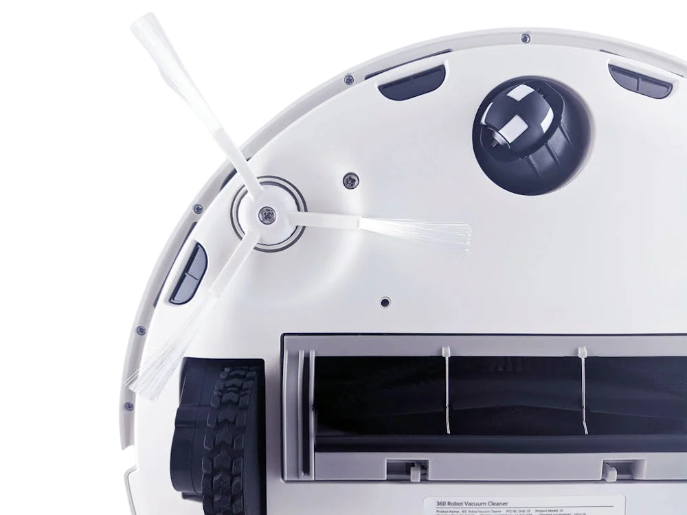 The bottom of a white robot vacuum cleaner with a brush on it