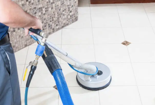 A person wearing yellow gloves is cleaning a white tile wall with a sponge.