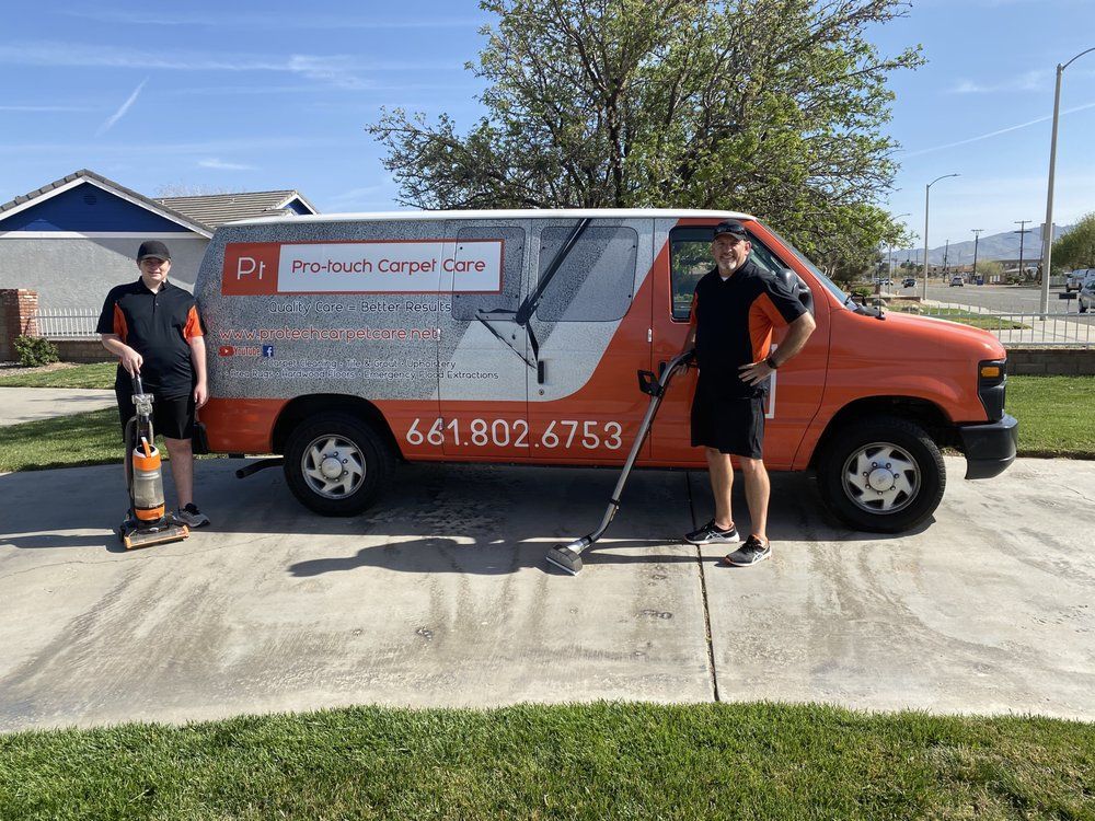 Two men are standing in front of a van with a vacuum cleaner attached to it.