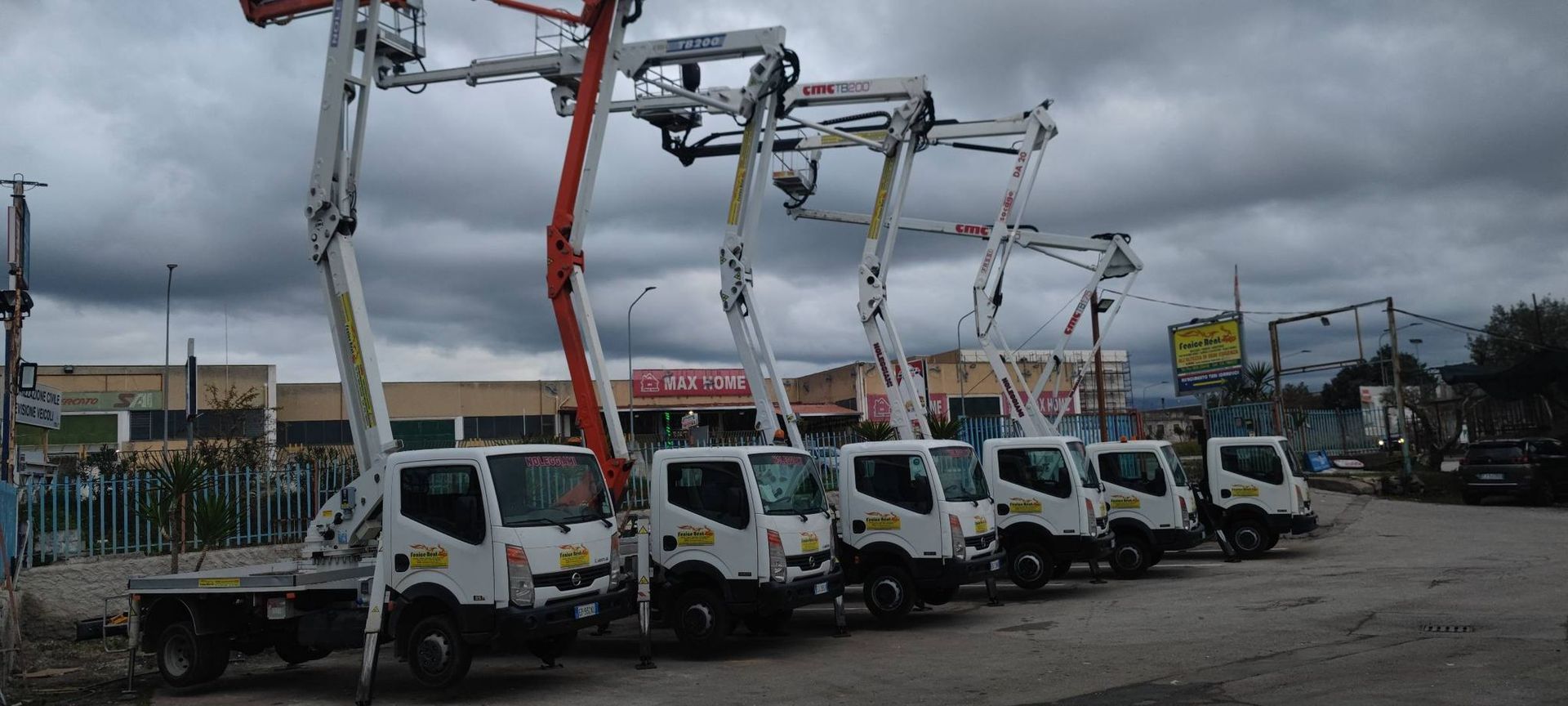 Fila di autopompe per calcestruzzo bianche parcheggiate sotto un cielo nuvoloso.